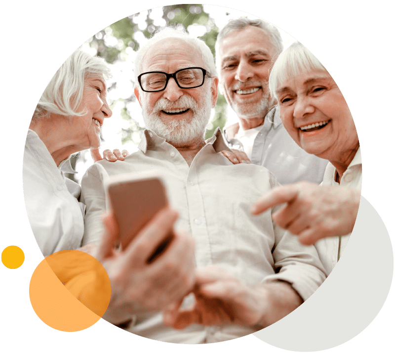 Eine Gruppe Senioren kommunizieren lachend über ein Mobiltelefon