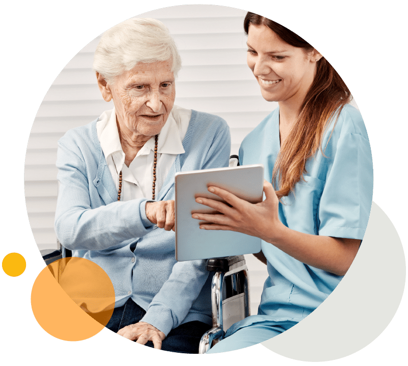 Eine ältere Dame im Rollstuhl kommuniziert mit ihrer Familie per Tablet im Seniorenheim